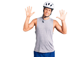 Young handsome man wearing bike helmet showing and pointing up with fingers number ten while smiling confident and happy.