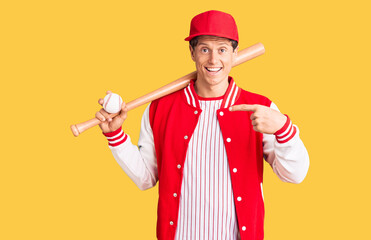 Young handsome man playing baseball holding bat and ball smiling happy pointing with hand and finger