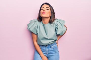 Young beautiful brunette woman wearing casual clothes. Standing throwing kiss over isolated pink background