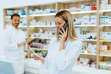 Male and female pharmacists working together at modern pharmacy.