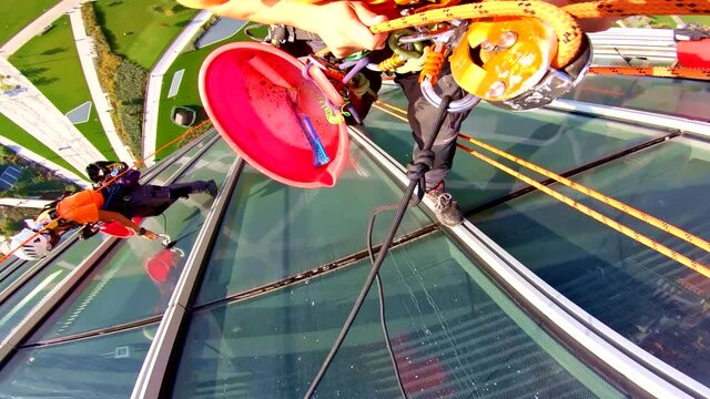 Abseiler construction worker on skyscrapper cleaning windows, point of view shot