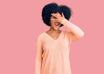 Fototapeta na wymiar Young african american girl wearing casual clothes peeking in shock covering face and eyes with hand, looking through fingers with embarrassed expression.