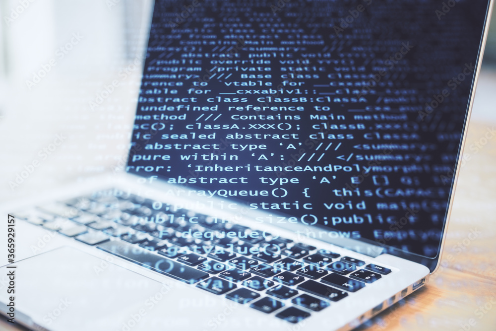 Fototapete Laptop computer on table with abstract coding backdrop with text