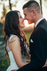 Sunshine portrait of happy bride and groom outdoor in nature location at sunset. Warm summertime. Happy couple with a beautiful bouquet of flowers. Wedding photo. Couple in love. Autumn wedding