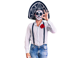 Man wearing day of the dead costume over background smiling positive doing ok sign with hand and fingers. successful expression.