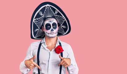 Man wearing day of the dead costume over background pointing down looking sad and upset, indicating direction with fingers, unhappy and depressed.