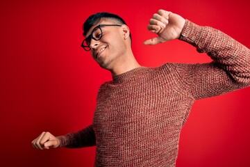 Young handsome hispanic man wearing nerd glasses over red background stretching back, tired and...
