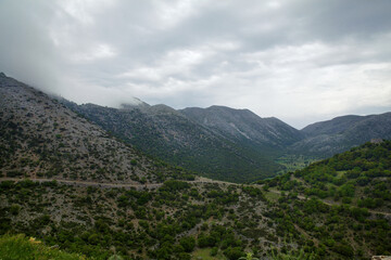 Fototapeta na wymiar Nature of the island of Crete in Greece. Panorama with a view of the mountains and mountain path, against a cloudy sky with clouds