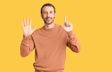Young handsome man wearing casual clothes showing and pointing up with fingers number seven while smiling confident and happy.