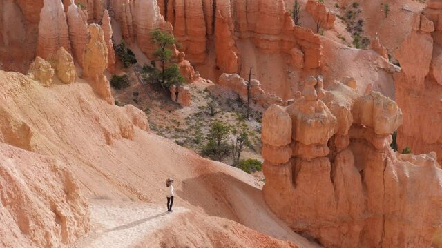 Slow motion shot of female tourist on trail looking at hoodoos in Bryce Canyon National Park in Utah, USA