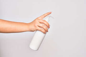 Hand of caucasian young woman holding bottle of body cream over isolated white background