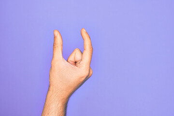 Hand of caucasian young man showing fingers over isolated purple background picking and taking invisible thing, holding object with fingers showing space