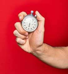 Beautiful hand of man holding stopwatch doing countdown over isolated red background