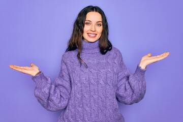 Young beautiful woman wearing casual turtleneck sweater standing over purple background smiling showing both hands open palms, presenting and advertising comparison and balance