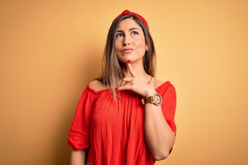 Young beautiful woman colorful summer style over yellow isolated background Thinking concentrated about doubt with finger on chin and looking up wondering