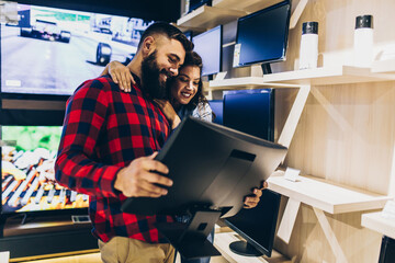 Young couple choosing flat panel monitor in an electronics store.