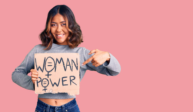 Young beautiful mixed race woman holding woman power banner smiling happy pointing with hand and finger