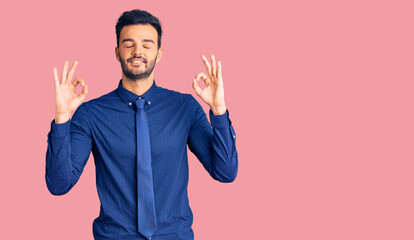 Young handsome hispanic man wearing business clothes relax and smiling with eyes closed doing meditation gesture with fingers. yoga concept.
