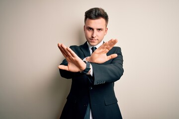 Young handsome business man wearing elegant suit and tie over isolated background Rejection expression crossing arms and palms doing negative sign, angry face