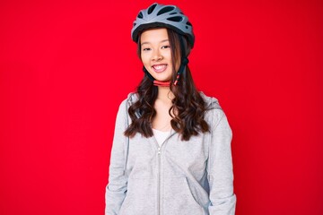 Young beautiful chinese girl wearing bike helmet looking positive and happy standing and smiling with a confident smile showing teeth
