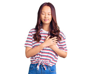 Young beautiful chinese girl wearing casual clothes smiling with hands on chest with closed eyes and grateful gesture on face. health concept.