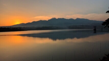 Landscape silhouette of mountains from the edge of the reservoir when the sun sets.