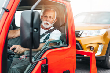 Handsome senior man working in towing service on the road and showing thumb up. Roadside assistance concept.