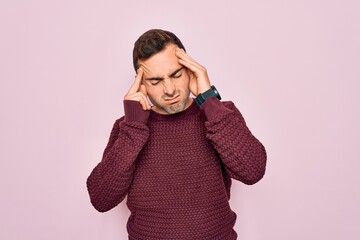 Young handsome man with blue eyes wearing casual sweater standing over pink background with hand on headache because stress. Suffering migraine.