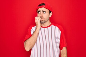Young handsome sporty man with blue eyes wearing striped baseball t-shirt and cap looking stressed and nervous with hands on mouth biting nails. Anxiety problem.