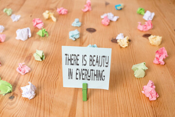 Handwriting text There Is Beauty In Everything. Conceptual photo the world is an endless array of magic Colored crumpled papers empty reminder wooden floor background clothespin