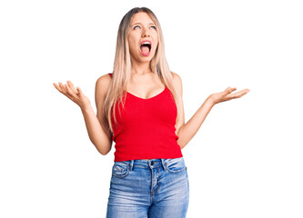 Young beautiful blonde woman wearing casual clothes crazy and mad shouting and yelling with aggressive expression and arms raised. frustration concept.