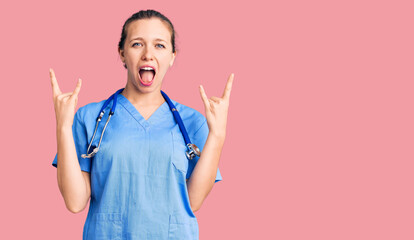 Young beautiful blonde woman wearing doctor uniform and stethoscope shouting with crazy expression...