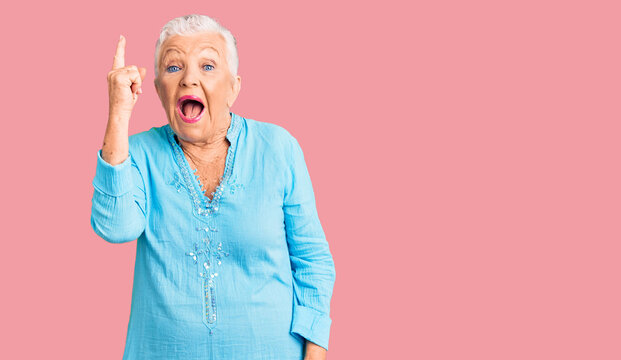 Senior beautiful woman with blue eyes and grey hair wearing summer dress pointing finger up with successful idea. exited and happy. number one.