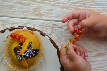 Cupcakes with berry currant, drizzled with chocolate. Fresh homemade cakes in child hands