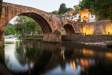 Landscape with the 16th century Royal Bridge over the river Ceira in Gois, Portugal, with the chapel of São Sebastião at the entrance of the bridge, on a late spring afternoon.