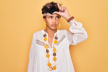 Young beautiful african american afro hippie woman wearing sunglasses and accessories making fun of people with fingers on forehead doing loser gesture mocking and insulting.