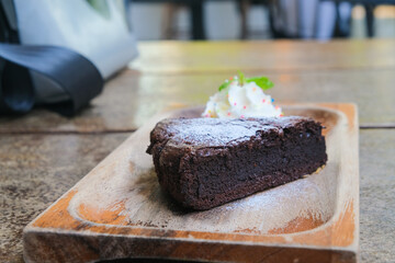 Homemade dark chocolate brownies cake topping with powder sugar and mint stacked on wood table with copy space.
