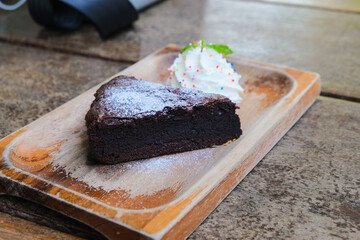 Homemade dark chocolate brownies cake topping with powder sugar and mint stacked on wood table with...