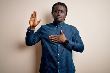 Young handsome african american man wearing casual shirt standing over white background Swearing...