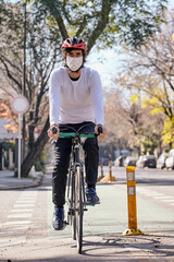 Obraz premium Young man on bicycle with protective mask against covid 19 driving on bike lane