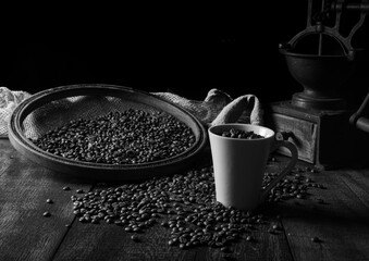 Roasted coffee on rustic wood, cup, grinder and more with black background, selective focus
