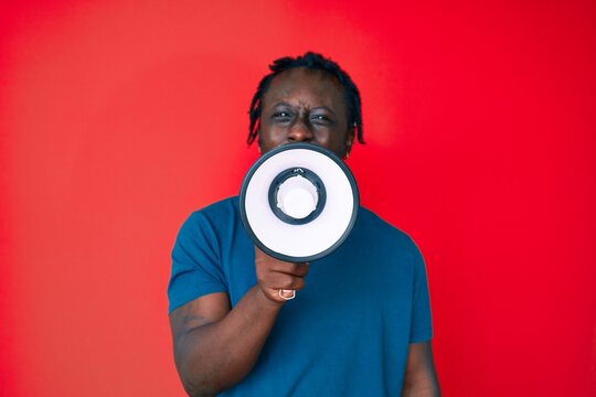 Young handsome african american man screaming using megaphone over isolated red background