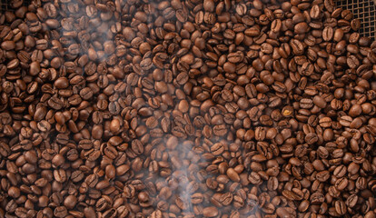 Roasted coffee on rustic sieve with smoke and with black background, Top view