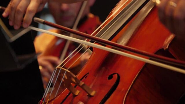 cellist playing cello in orchestra slow motion