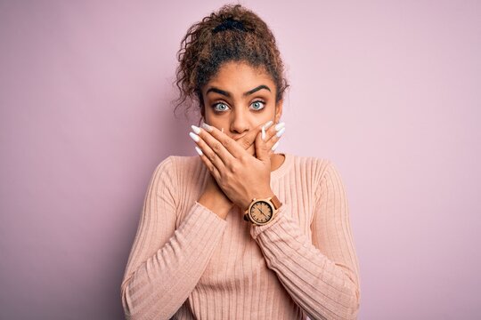 Young beautiful african american girl wearing casual sweater standing over pink background shocked covering mouth with hands for mistake. Secret concept.