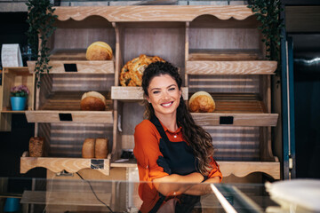 Beautiful young female worker working in bakery.