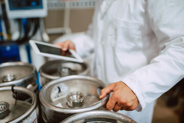  Closeup of tablet computer in hand of professional caucasian technologist expert in white uniform  in production plant - food or drink factory