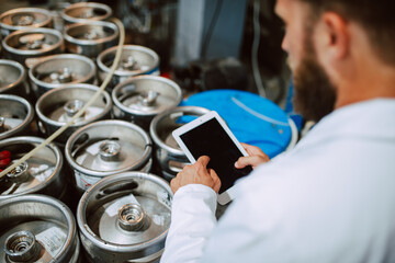  Closeup of tablet computer in hand of professional caucasian technologist expert in white uniform  in production plant - food or drink factory