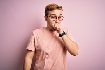 Young handsome redhead man wearing casual t-shirt standing over isolated pink background feeling unwell and coughing as symptom for cold or bronchitis. Health care concept.