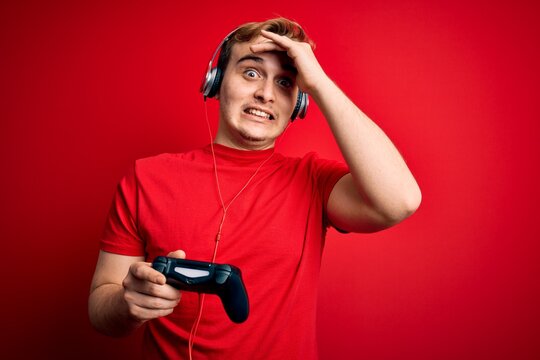 Young Handsome Redhead Gamer Man Playing Video Game Using Headphones And Joystick Stressed And Frustrated With Hand On Head, Surprised And Angry Face